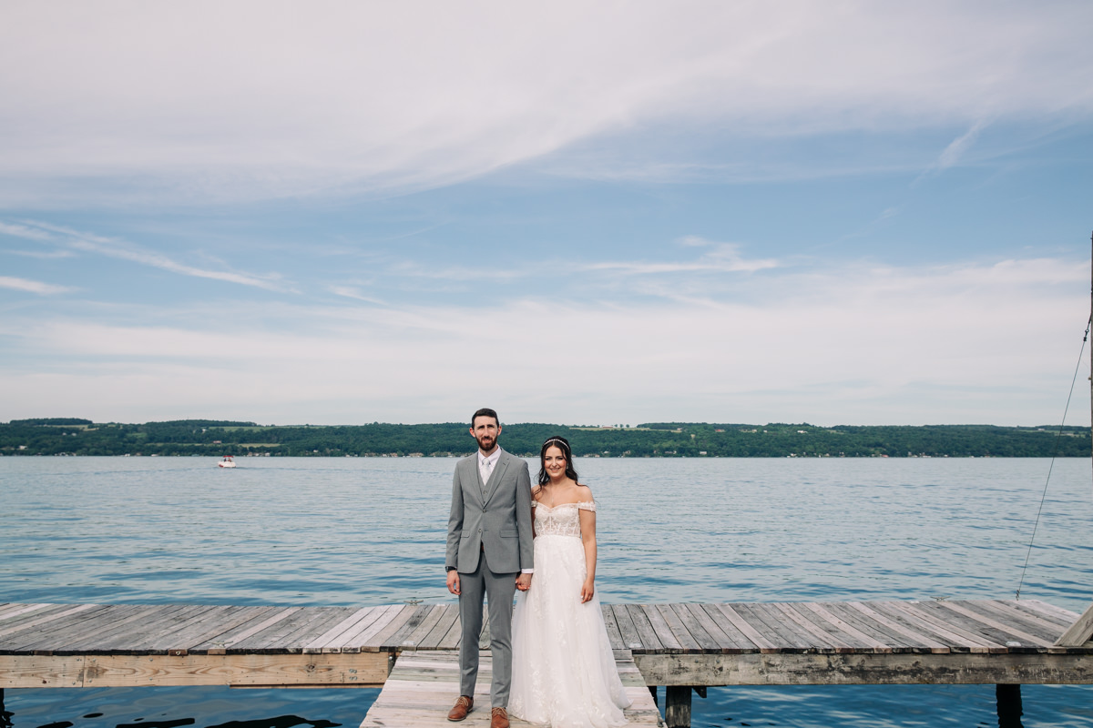 bride-and-groom-stand-on-cayuga-lake-in-the-finger-lakes-region-NY