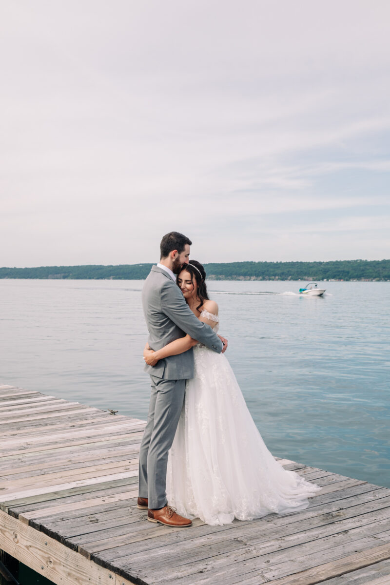 bride-and-groom-stand-on-cayuga-lake-in-the-finger-lakes-region-NY